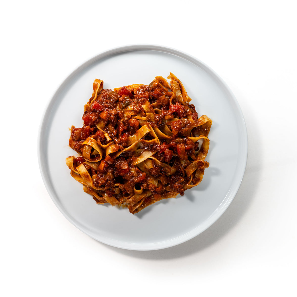 Bord met brede lintpasta en Bolognese, van bovenaf gezien