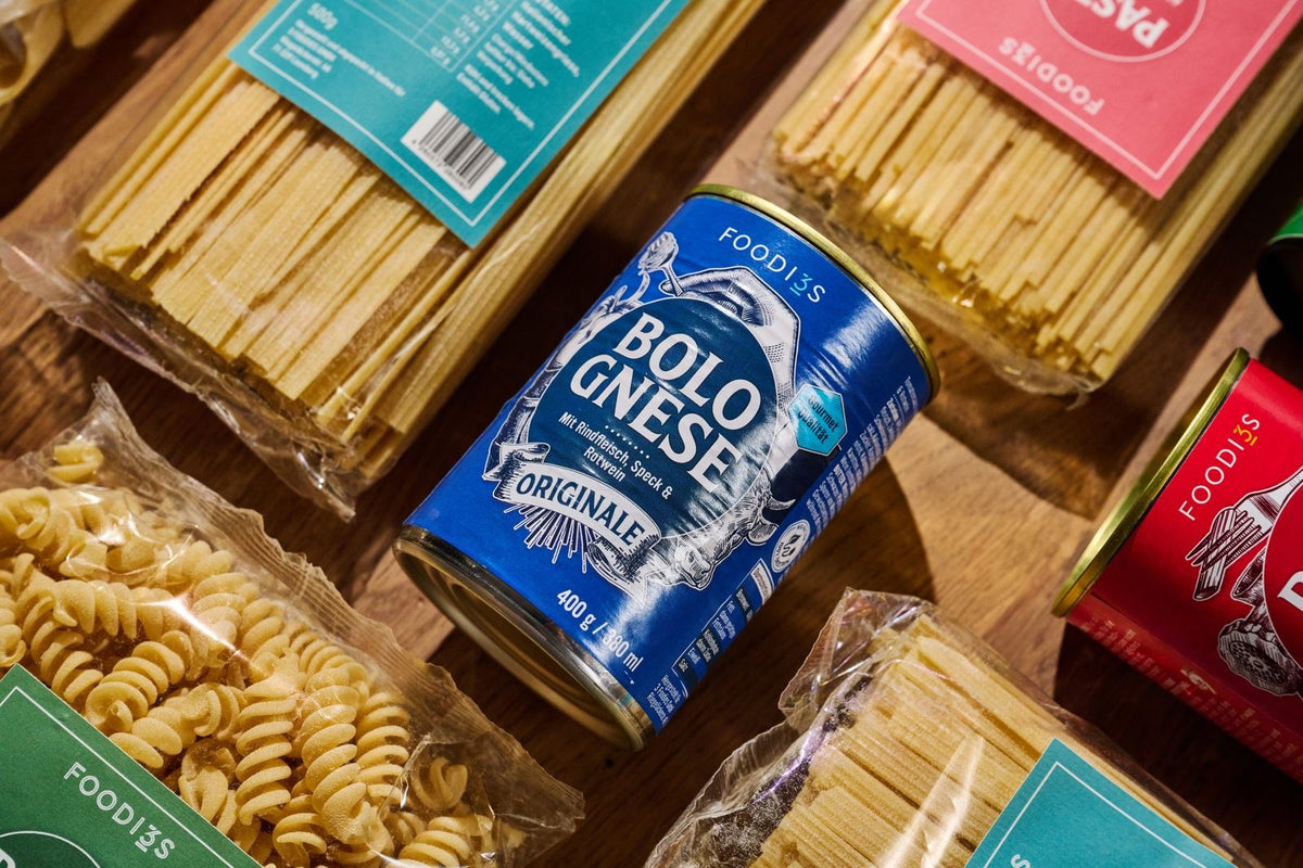 Pasta-Packungen und eine Dose Bolognese Originale auf einem Holztisch